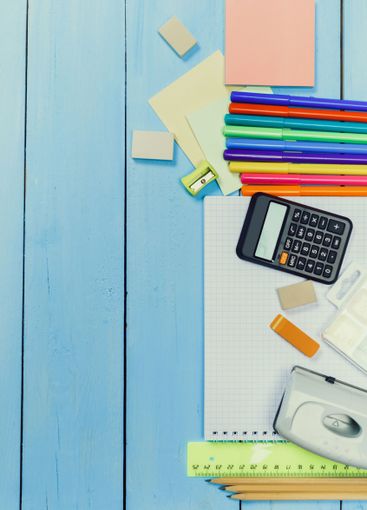 Colorful stationery supplies arranged on a blue wooden...