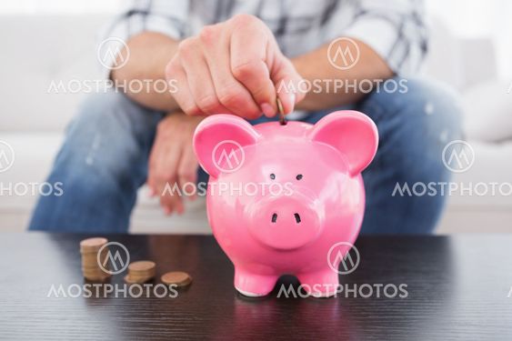 A man putting coins in piggy bank