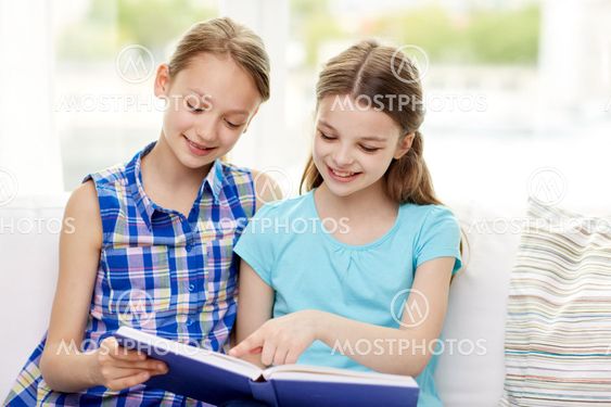 two happy girls reading book at home