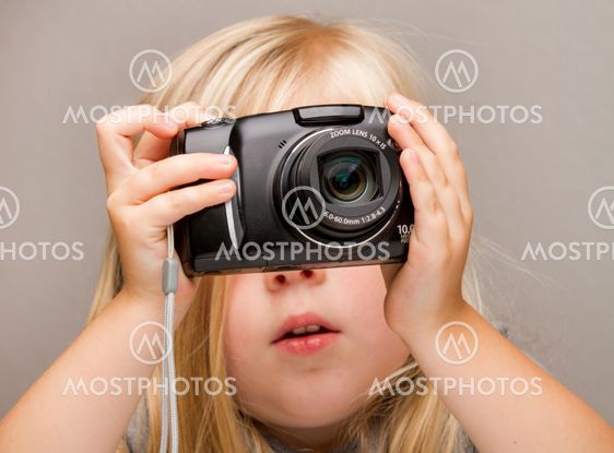 Young child holding a camera taking a picture