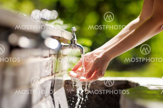 Woman washing hands in a city fountain