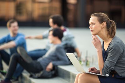 Portrait of a sleek young woman, using laptop computer,...