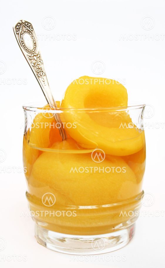 Peaches in a sweet syrup in a glass isolated on the white