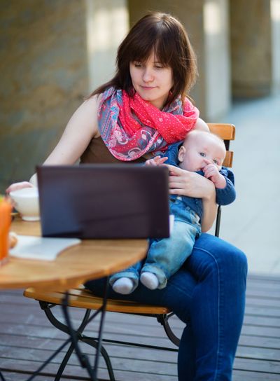 Young mother with her baby boy working in cafe