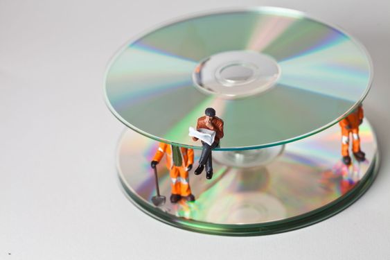 Miniature people in action with CDs