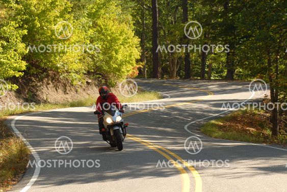 One motorcyclist riding along a winding road