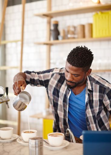 Barista, man and coffee preparation with milk in cafe...