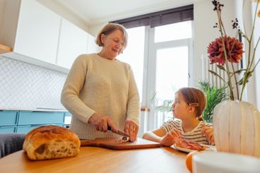 An elderly woman prepares breakfast for her...
