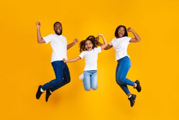 Portrait of emotional black family jumping at studio