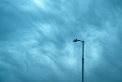Street light lamp on a tall post against moody dramatic sky