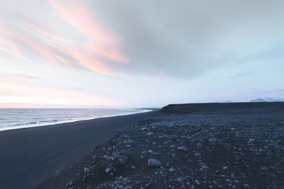 seashore with rocks and cloudy sky at sunset,...