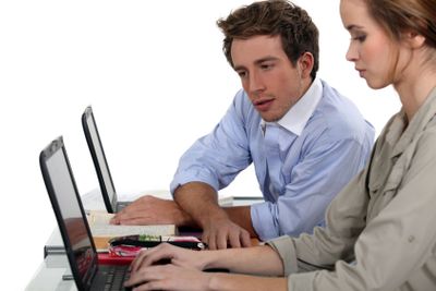 Two colleagues sat with laptops