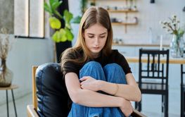 Sad unhappy thoughtful young woman sitting in armchair at...