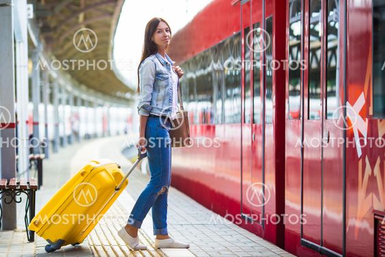 Young girl with luggage on the platform waiting for...