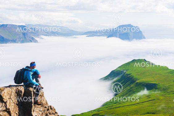 Hiker sitting on cliff, Mykines, Faroe Islands