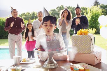 Birthday cake, big family and son blow candles with...