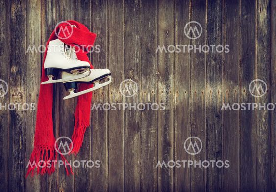 Old ice skates hanging on rustic wooden wall