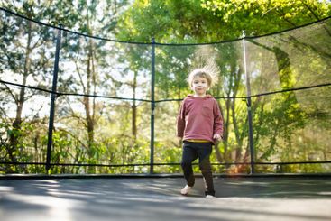 Little boy jumping on a trampoline in a backyard on warm...