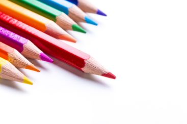 Vibrant colored pencils arranged in a row on a clean...