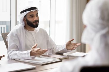 Young Arabic businessman in traditional kandora engaged...