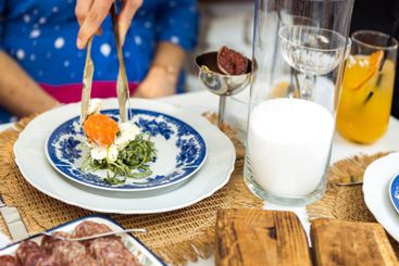 A waiter serves fresh salmon salad onto a blue-decorated...