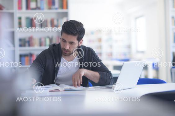 student in school library using laptop for research
