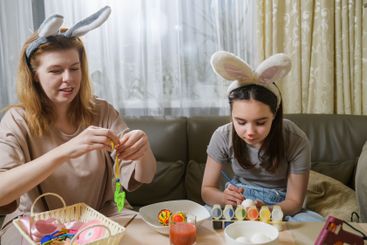 Mother And Daughter Decorating Easter Eggs At Home.