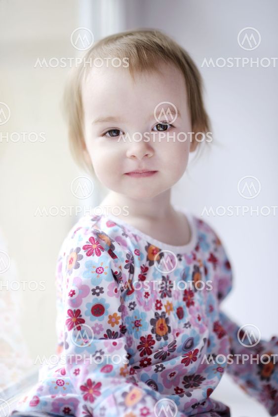 Two years old girl sitting by the window
