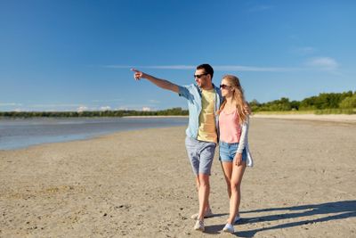 happy couple walking along summer beach