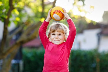 Little adorable toddler girl playing with ball outdoors....