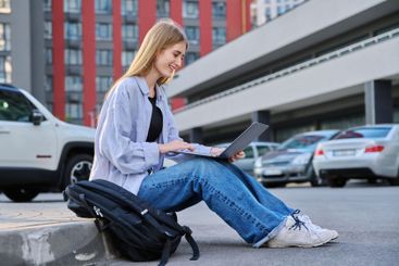 Young female college student using laptop computer outdoor
