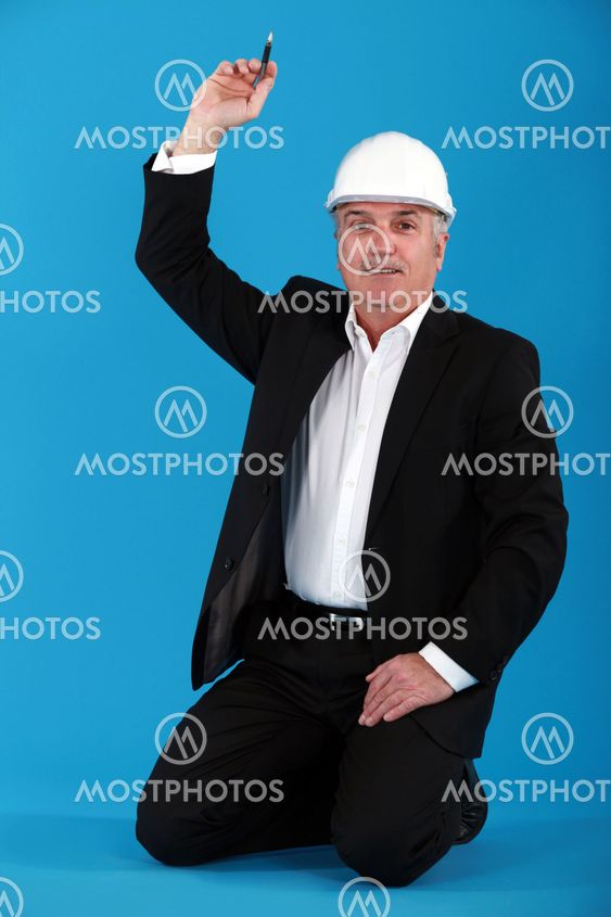 Mature architect kneeling on the floor with arm raised