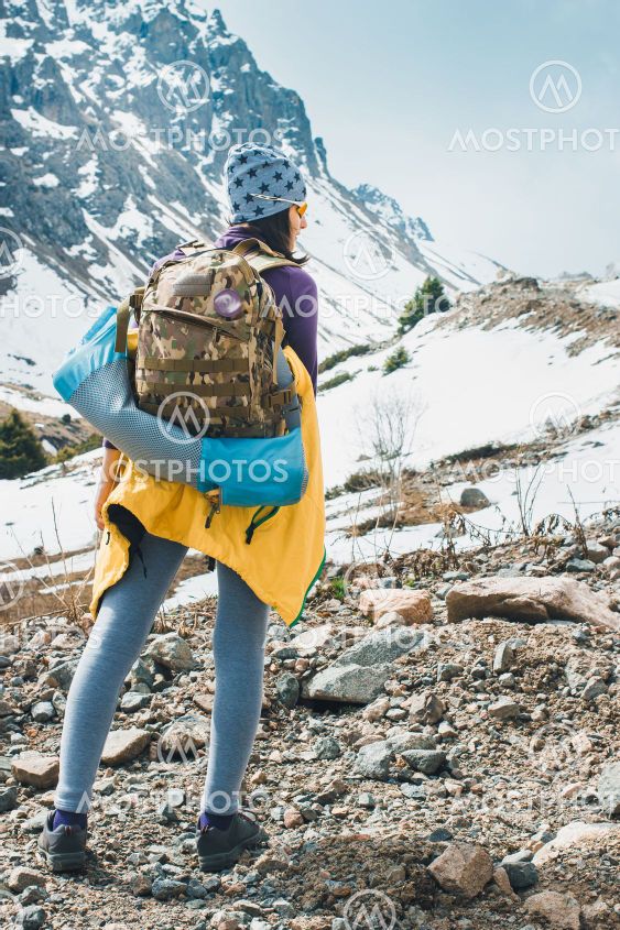 Traveling girl with backpack hiking in the mountains,...