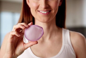 The young Caucasian woman holds the diaphragm vaginal...