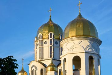 Shiny Christian church with golden domes, blue clear sky