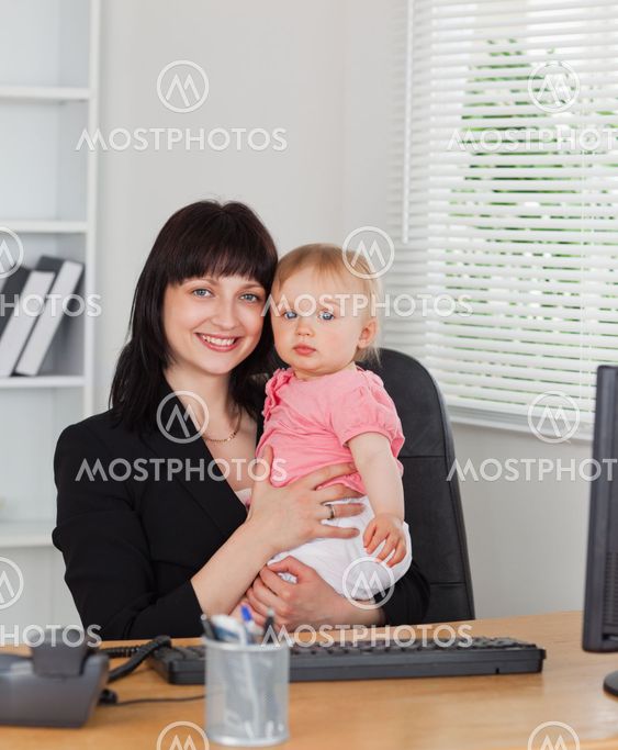 Attractive brunette woman posing while holding her baby on her knees