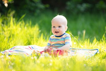 Baby boy with apple on family garden picnic