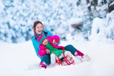 Mother and child sledding in a snowy park