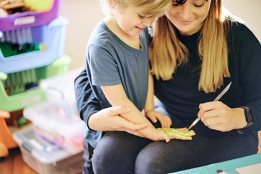 Mother, child and painting hand in home, playing and...