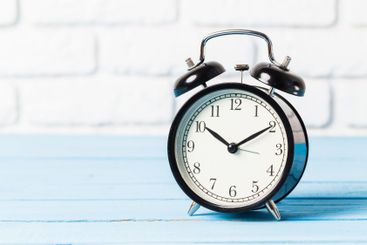 Black vintage alarm clock on wooden table