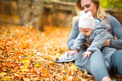 Mother and her little daughter play cuddling on autumn...