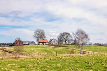 Winding road on the farmland to a farm on a hill at spring