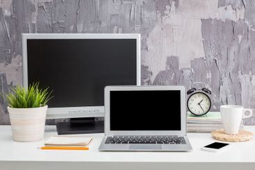 Minimalistic workspace with laptop, monitor, clock, and...