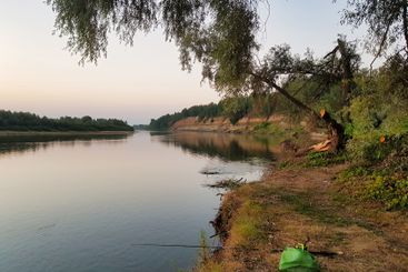 Tranquil evening by the riverside with fishing gear and...