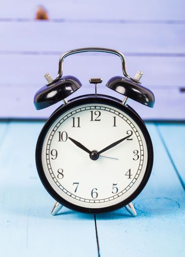 Black vintage alarm clock on wooden table