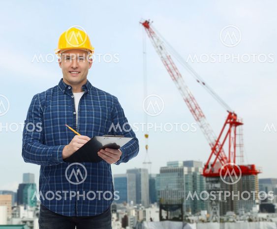 smiling male builder in helmet with clipboard