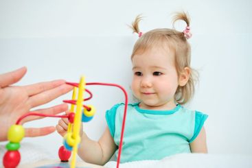 toddler happy playing with a toy and a parent.