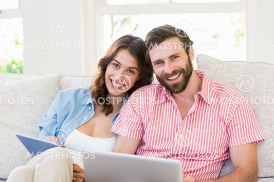 Portrait of couple using digital tablet and laptop