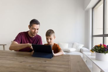 Dad and son making purchase on internet using digital...