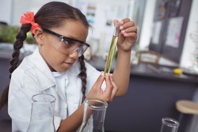 Concentrated student examining yellow chemical in test...